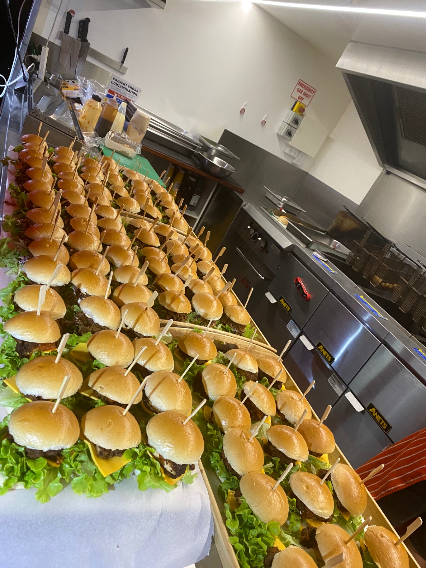 Mini smash burgers lined up on the prep bench for a catered function